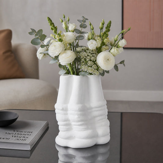 White textured ceramic flower vase with fresh blooms placed on modern coffee table in elegant living room.