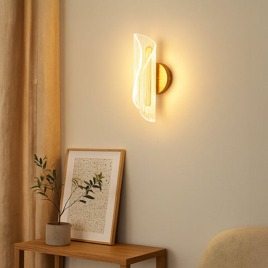 Gold metal wall light with sculpted clear glass shade adding warm ambient lighting to a modern elegant interior.