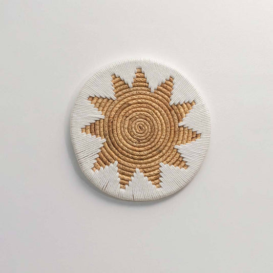 Round handcrafted natural seagrass wall basket with sunburst pattern on white background image.