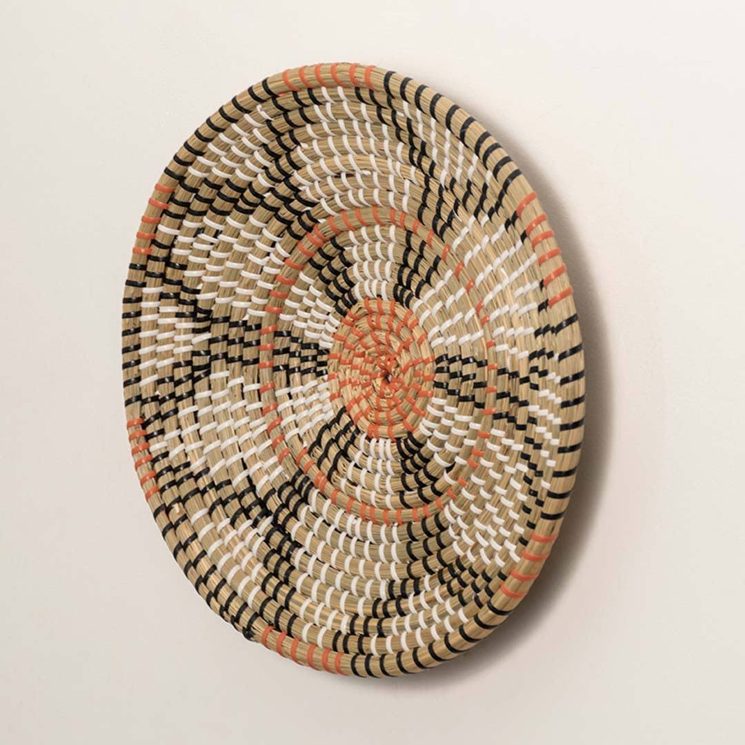 Side view of handcrafted natural seagrass wall basket with orange and black geometric block pattern for boho wall decor.
