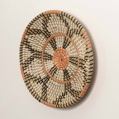 Side view of handcrafted natural seagrass wall basket with orange and black geometric block pattern for boho wall decor.
