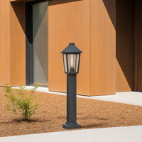 Modern black aluminum tapered glass bollard post light fixture on gravel landscape path for contemporary estate yard entry.
