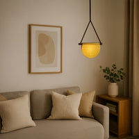 Black metal pendant light with amber glass shade enhancing cozy bedroom decor with warm lighting.