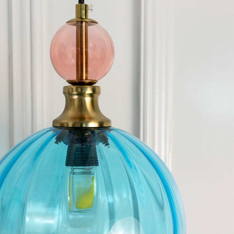 Detailed view of turquoise blue glass pendant light with brass fittings highlighting refined elegance.