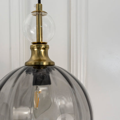 Closeup of smoky grey glass pendant light with antique brass hardware showcasing premium craftsmanship.