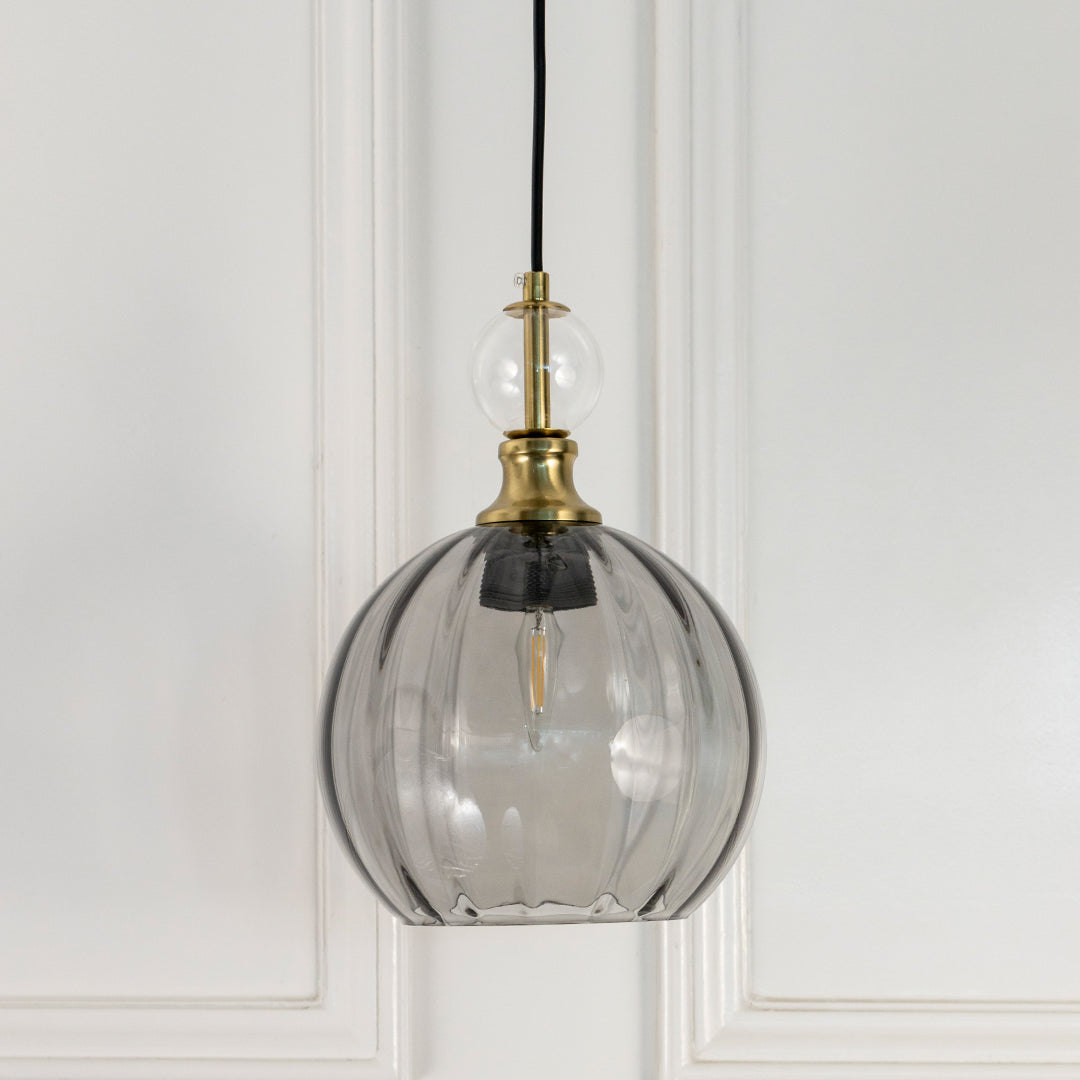 Smoky grey glass globe pendant light with brass fittings crafted for modern living and dining spaces.