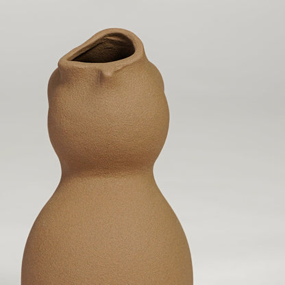 Close view of brown ceramic sculpted vase highlighting organic curved form and smooth matte finish.