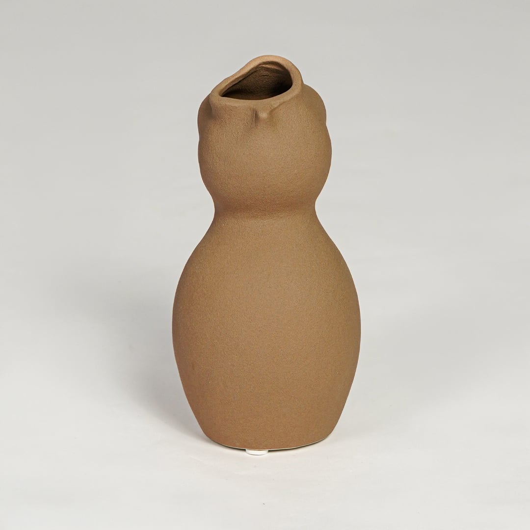 Brown ceramic sculpted vase with smooth organic silhouette isolated on clean white background for modern decor styling.