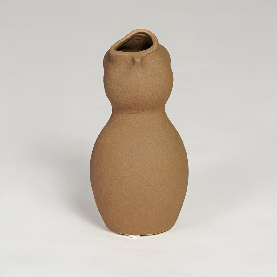 Brown ceramic sculpted vase with smooth organic silhouette isolated on clean white background for modern decor styling.