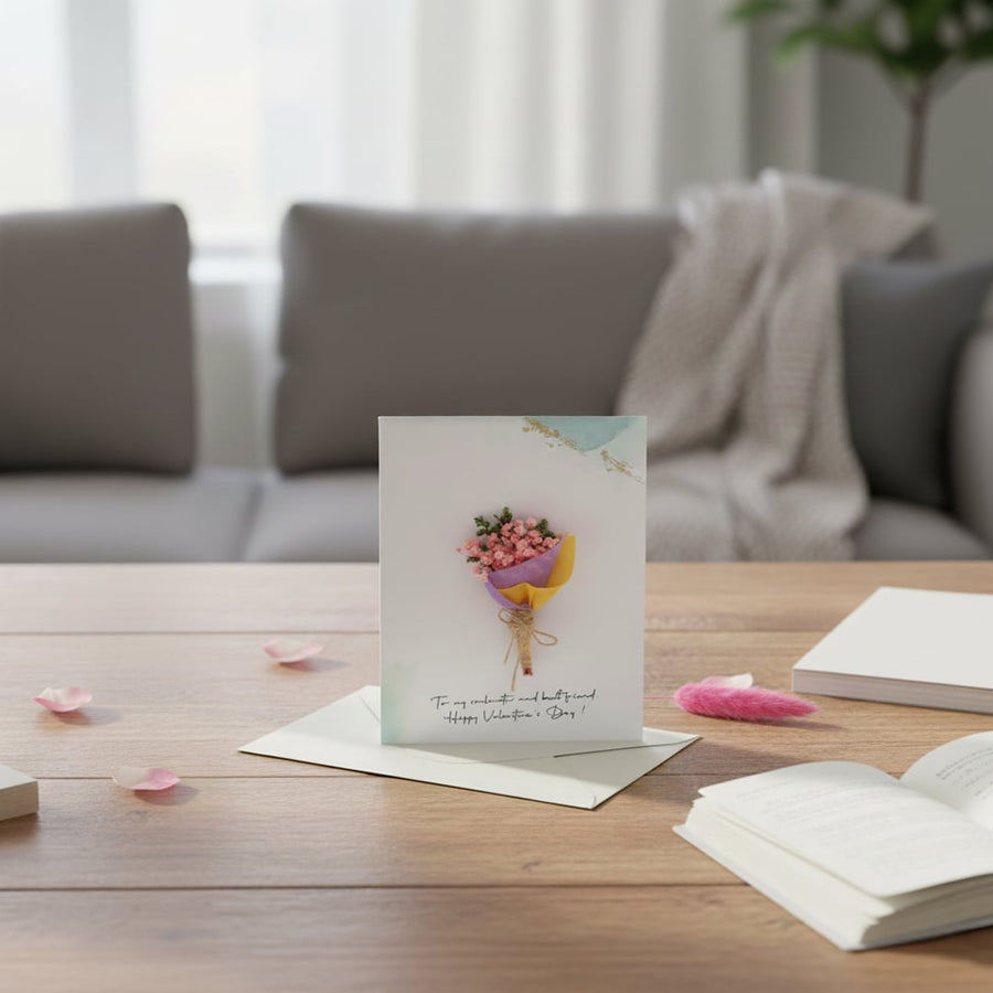A handmade mini flower bouquet greeting card standing on a wooden living room coffee table in front of a blurry grey couch.
