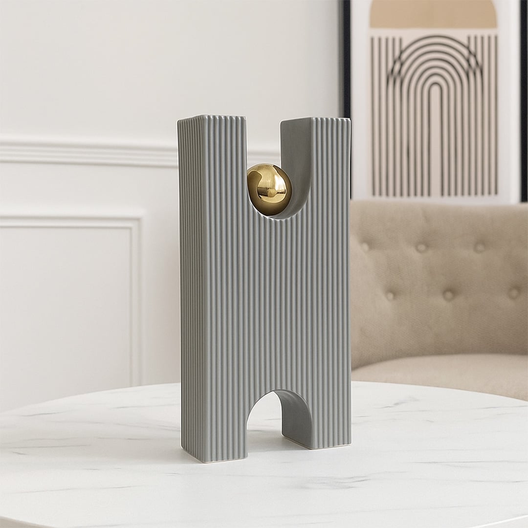 A modern grey sculptural decor piece with a gold sphere displayed on a minimal pedestal creating a stylish artistic accent for contemporary home interiors.