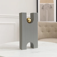 A modern grey sculptural decor piece with a gold sphere displayed on a minimal pedestal creating a stylish artistic accent for contemporary home interiors.