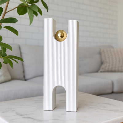 Tall white modern sculpture with ribbed texture and gold sphere styled in a clean minimal setup adding artistic elegance to decor.