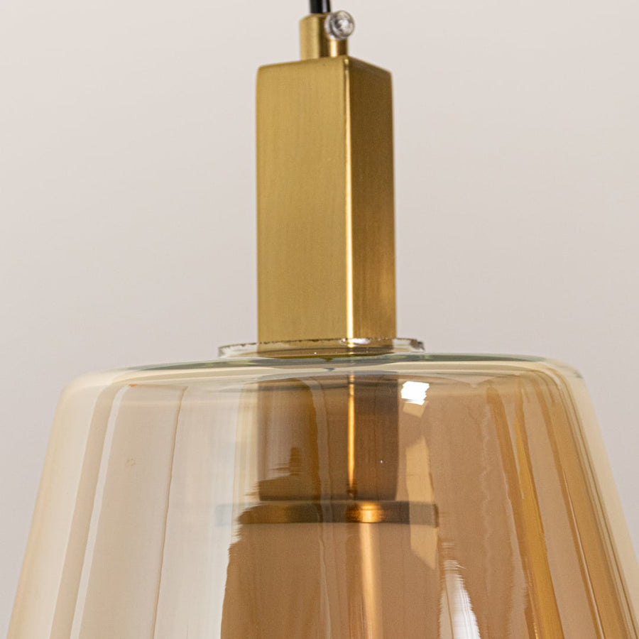 Closeup of amber glass and gold metal pendant light highlighting premium finish and craftsmanship.