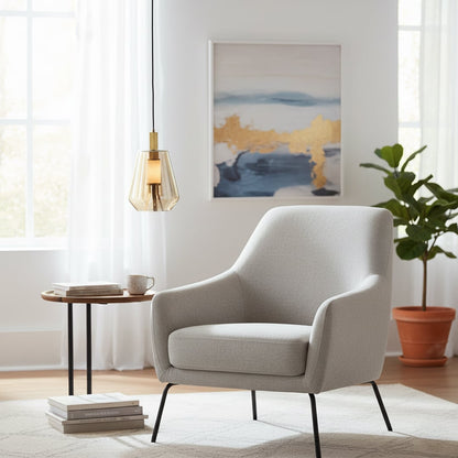 Amber glass and gold metal pendant light adding warm elegance beside the armchair in modern interiors.