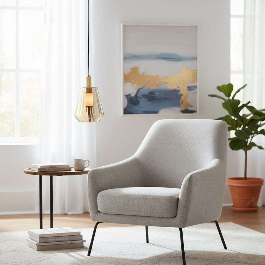 Amber glass and gold metal pendant light adding warm elegance beside the armchair in modern interiors.