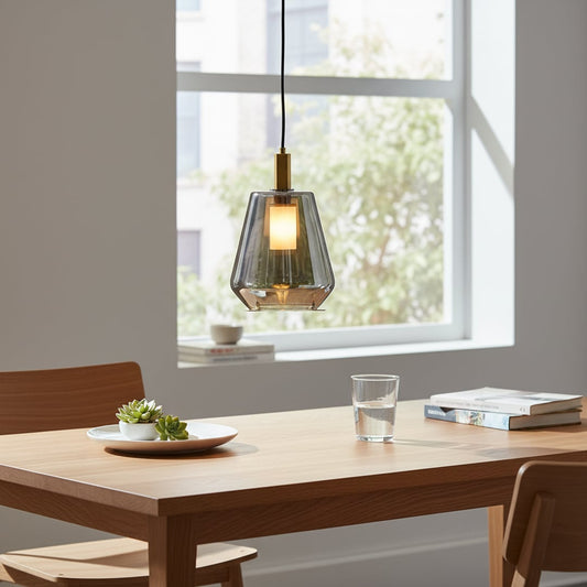 A modern dining space with a smoked glass pendant light hanging above a wooden table while the light is on creating a warm and inviting setting.