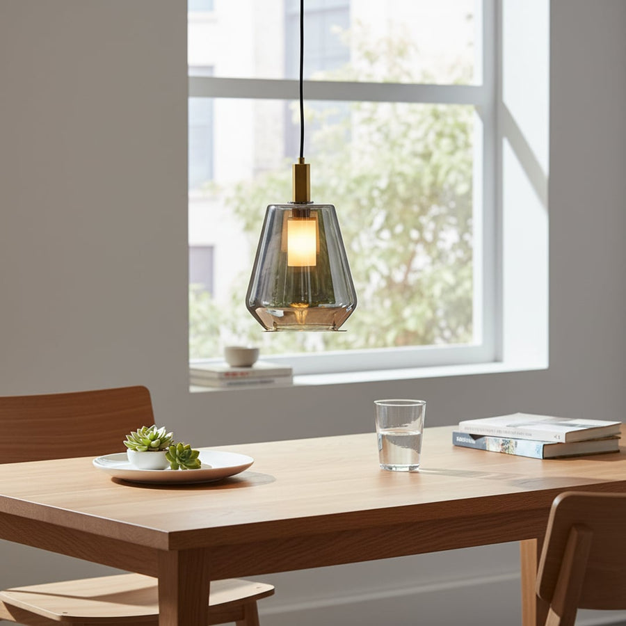 Smoke glass and gold metal pendant light adding modern elegance above the dining table in stylish interiors.