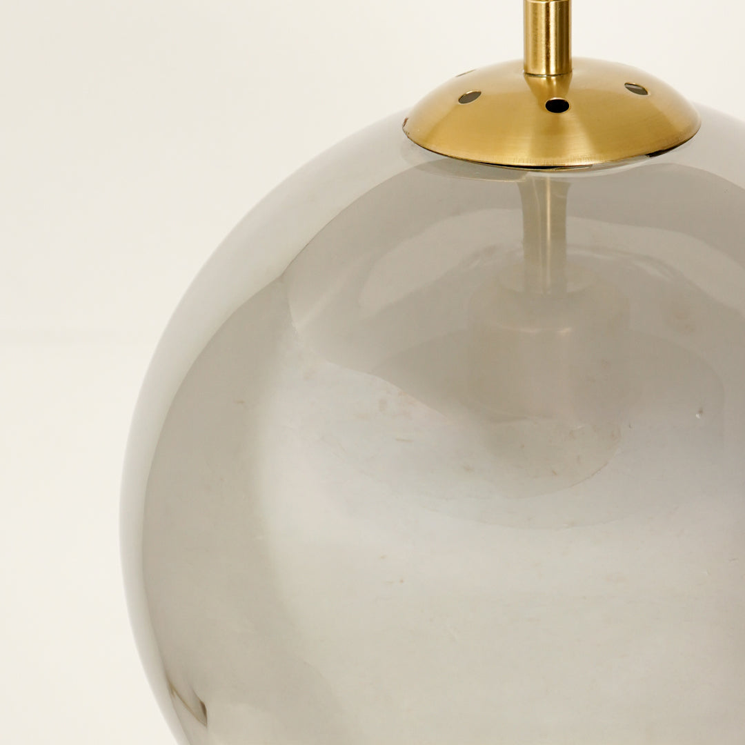 Clear glass globe pendant light with gold metal accents for elegant modern ceiling lighting decor.