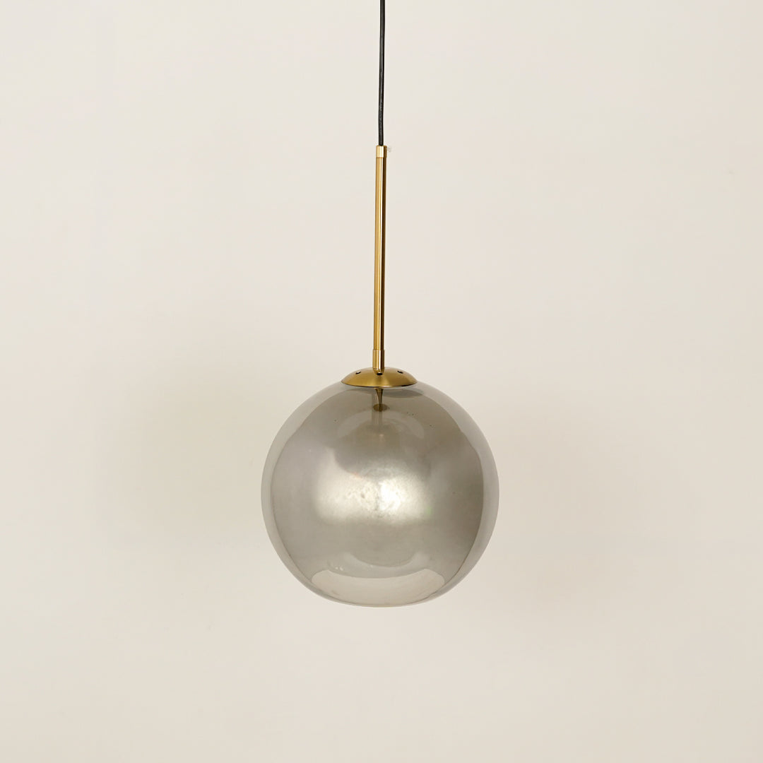 Smoked glass globe pendant light with gold cord for refined contemporary interiors.