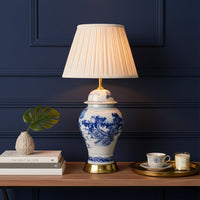 Blue and white ceramic table lamp with pleated fabric shade styled on console table creating elegant classic living room lighting.
