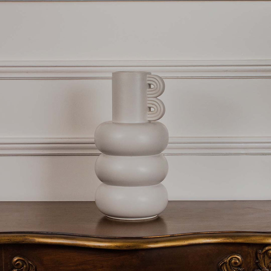 A contemporary neutral vase presented on a clean white background with its bold stacked form and artistic side accent standing out clearly.
