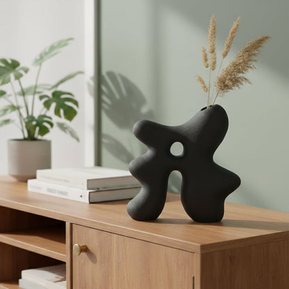 Dark grey ceramic abstract hollow vase styled on console table for modern living room decor accent.