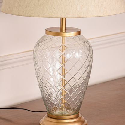 Closeup of gold metal table lamp with crystal glass base for elegant luxury tabletop decor styling ideas.