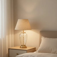 Gold metal table lamp with crystal glass base and fabric shade for elegant modern bedroom lighting decor.