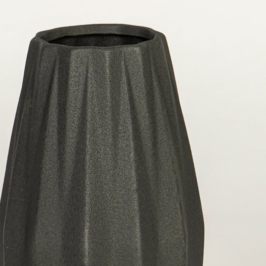Close view of black ceramic vase highlighting ribbed texture matte finish and tapered shape for table styling.