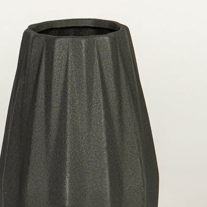Close view of black ceramic vase highlighting ribbed texture matte finish and tapered shape for table styling.