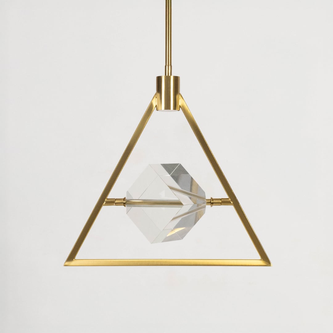 Pendant light with golden triangular frame and clear crystal centerpiece shown off on white background.
