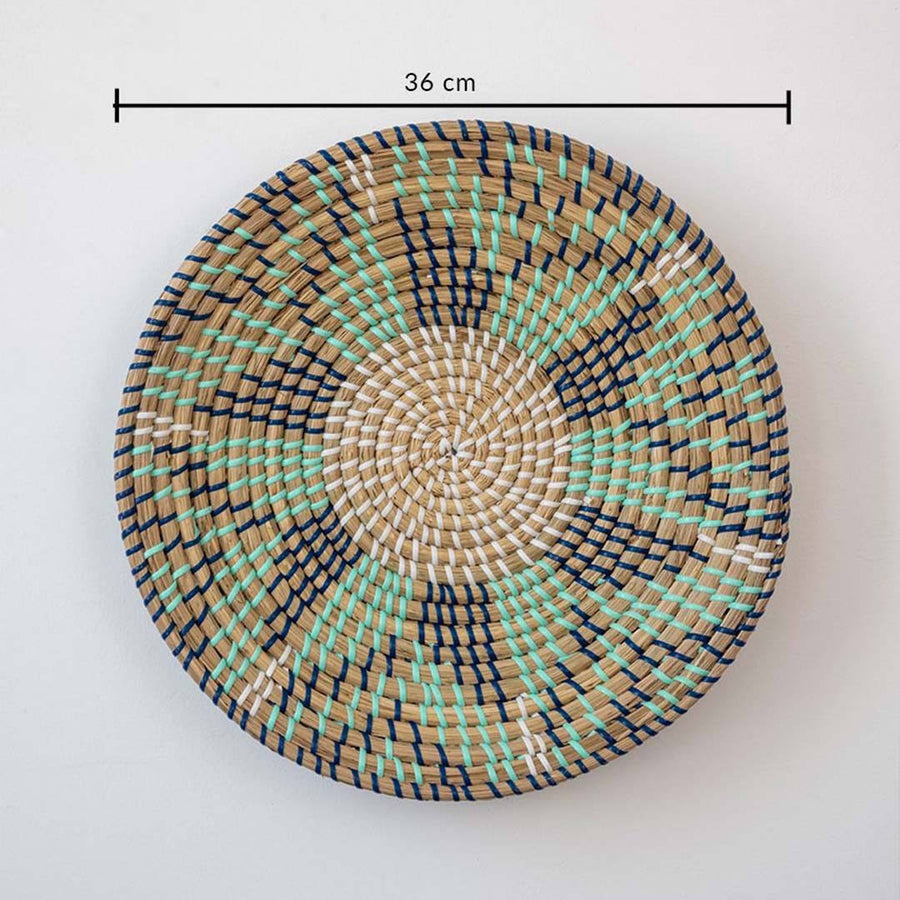 Handwoven seagrass round wall basket decor in beige green and brown with spiral woven pattern and size guide on white.