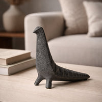 Dark grey ceramic abstract animal decor sculpture placed on wooden table in modern living room styling setup.