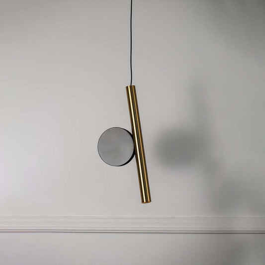 Minimal wall light with slim gold rod and round backplate placed against neutral wall background showcasing sleek modern lighting decor aesthetic.