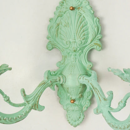 Closeup image of distressed green cast aluminium candelabra wall sconce for elegant rustic living room interior styling.