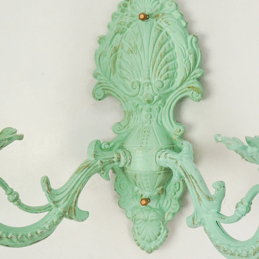 Closeup image of distressed green cast aluminium candelabra wall sconce for elegant rustic living room interior styling.