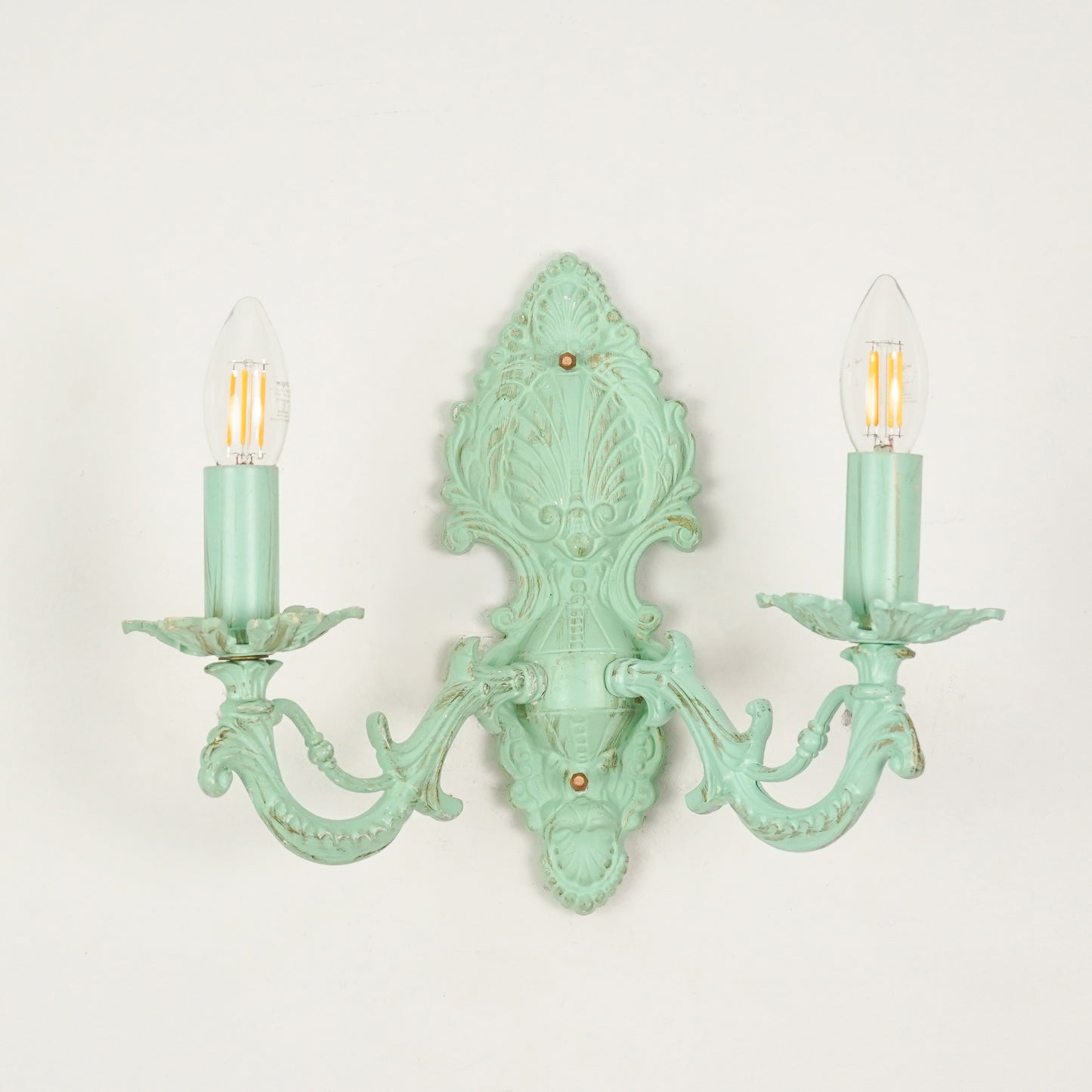 White background image of distressed green cast aluminium candelabra wall sconce for elegant rustic living room styling.