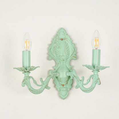 White background image of distressed green cast aluminium candelabra wall sconce for elegant rustic living room styling.