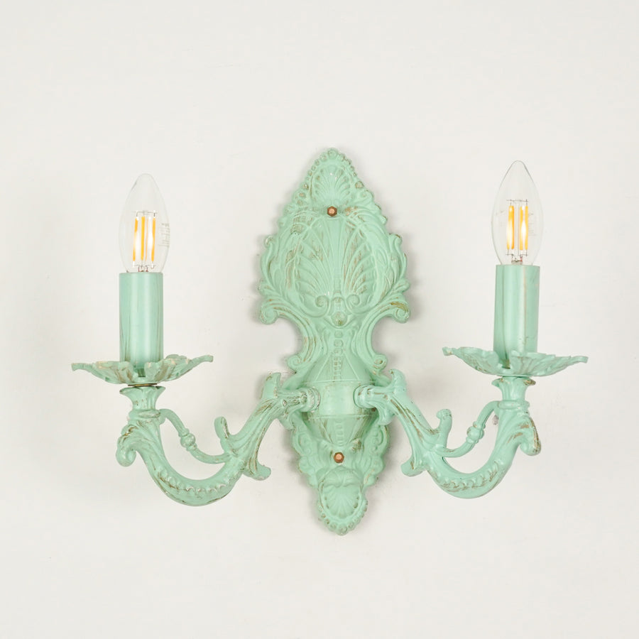 White background image of distressed green cast aluminium candelabra wall sconce for elegant rustic living room styling.