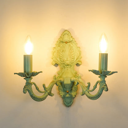 White background image of illuminated distressed green cast aluminium wall sconce for elegant rustic living room styling.