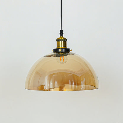 Amber glass dome pendant light illuminated with warm glow and brass metal accents for stylish ceiling lighting decor.
