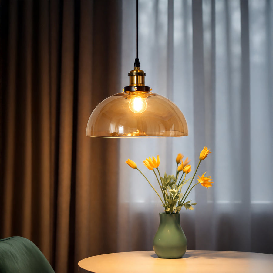 Amber glass dome pendant light above side table adding warm ambient lighting and modern elegance to home decor.