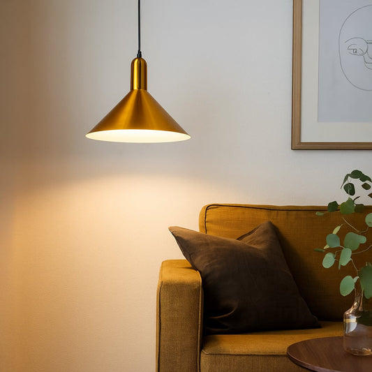 A modern gold metal pendant light glowing warmly above a mustard sofa creating soft ambient lighting ideal for living rooms reading corners and cozy interiors.