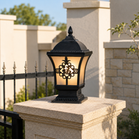 Ornate black metal scroll pattern frosted glass pillar lantern light on stone gate post for luxury residential driveway entry.