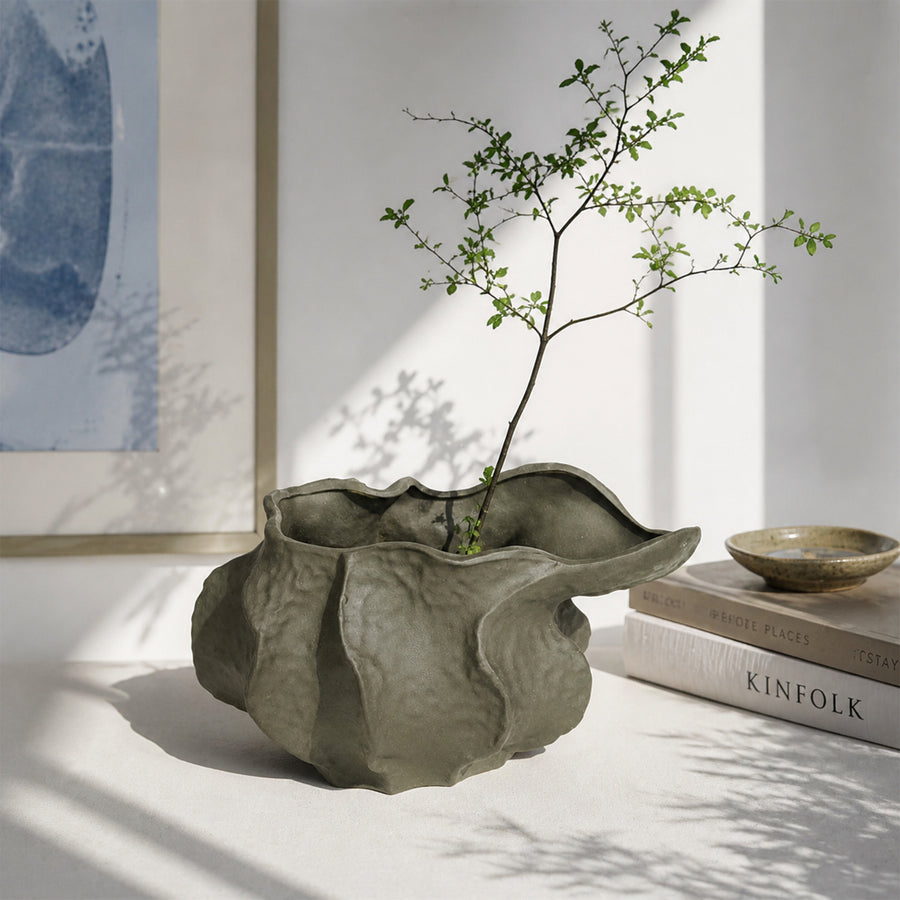 Grey textured ceramic planter bowl with branch stems placed on table for modern decor styling.