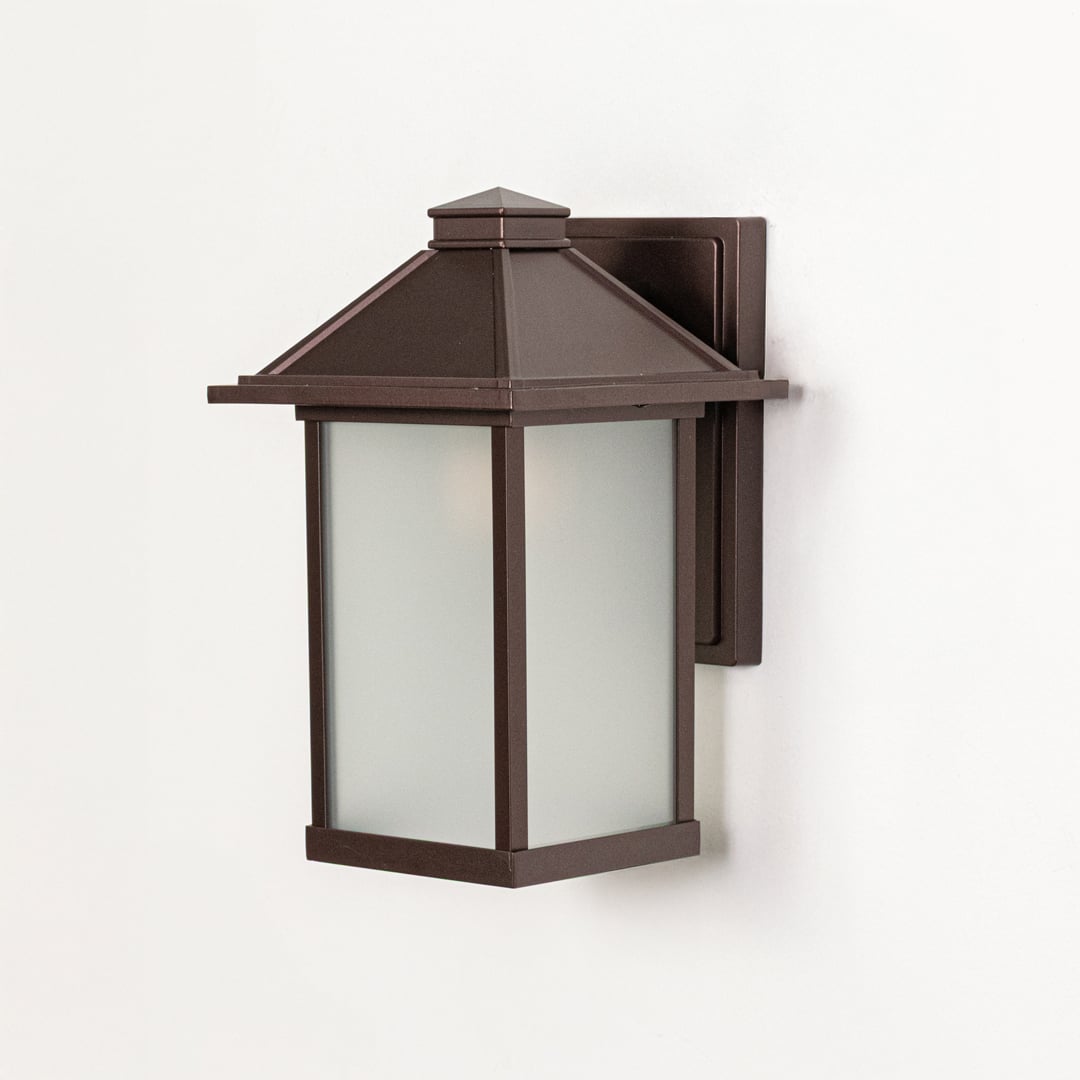 Brown metal wall mounted outdoor lantern switched off on white background emphasizing clean structure and frosted glass panels.