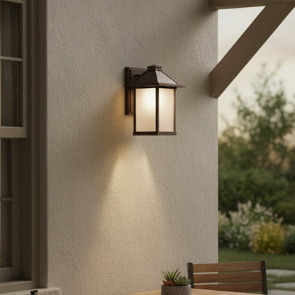 Brown metal outdoor wall lantern with frosted glass panels mounted on exterior wall adding classic architectural lighting appeal.