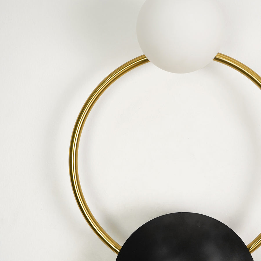Detailed close up view of a modern gold brass loop wall sconce highlighting the clean round geometric framework.