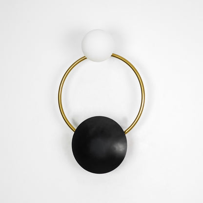 Contemporary gold brass hoop wall sconce featuring an unlit frosted glass globe bulb isolated on white backdrop.